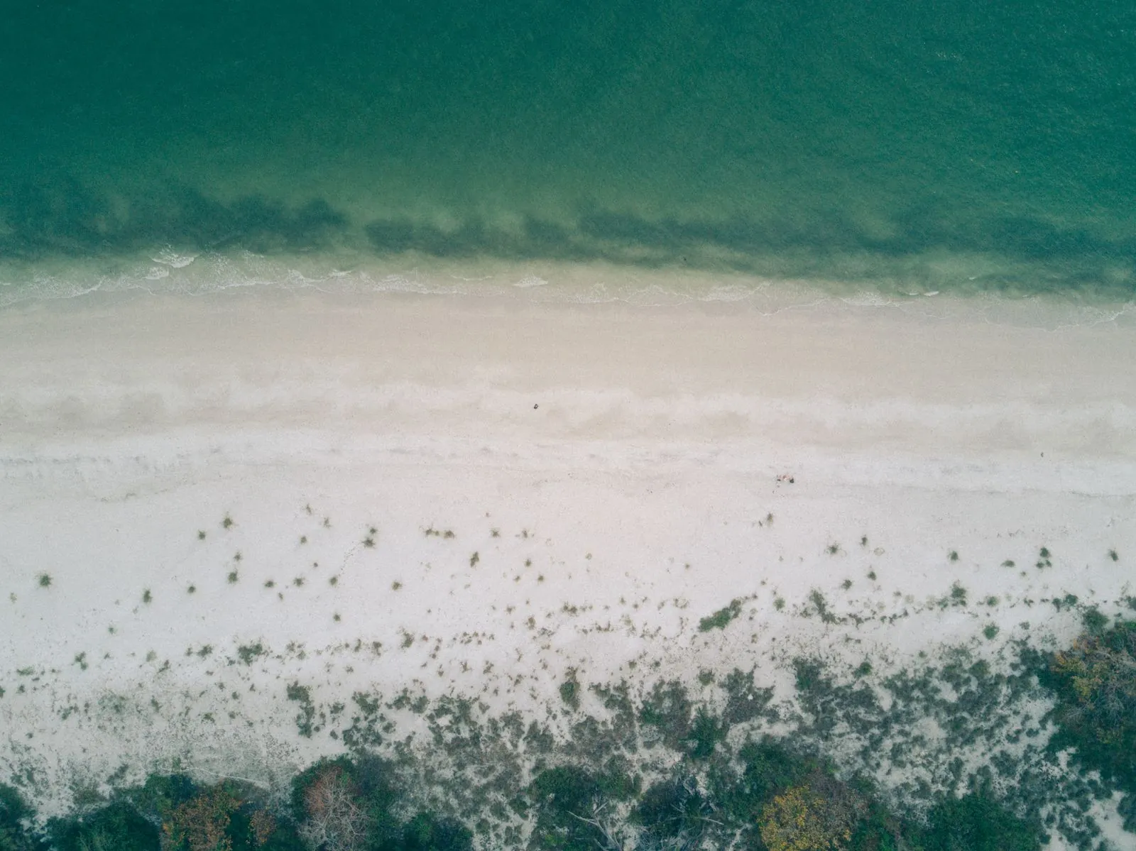 Land near Destin, Florida — aerial view of waves rolling onto a white sand beach